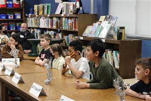 Students sit in a row at a table in a school library