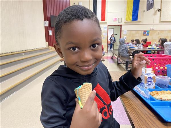 Student smiles at camera in a cafeteria
